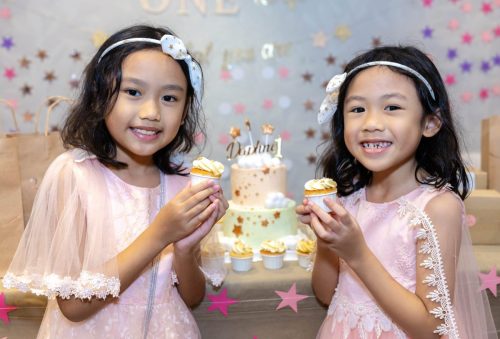 Girls wearing a pink dress holding a birthday cakes.