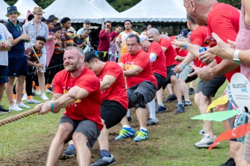 A group of Men in a red shirts performing a Tug of War game at Highland games Kl.